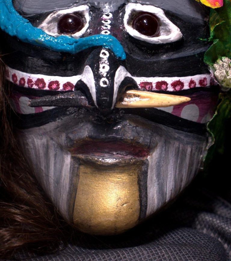 Jungle Tribe – Face Detail with Bone Piercing Close-up of the Jungle Tribe sculpture’s face showing maroon eyes, nose bone piercing, and painted gold chin